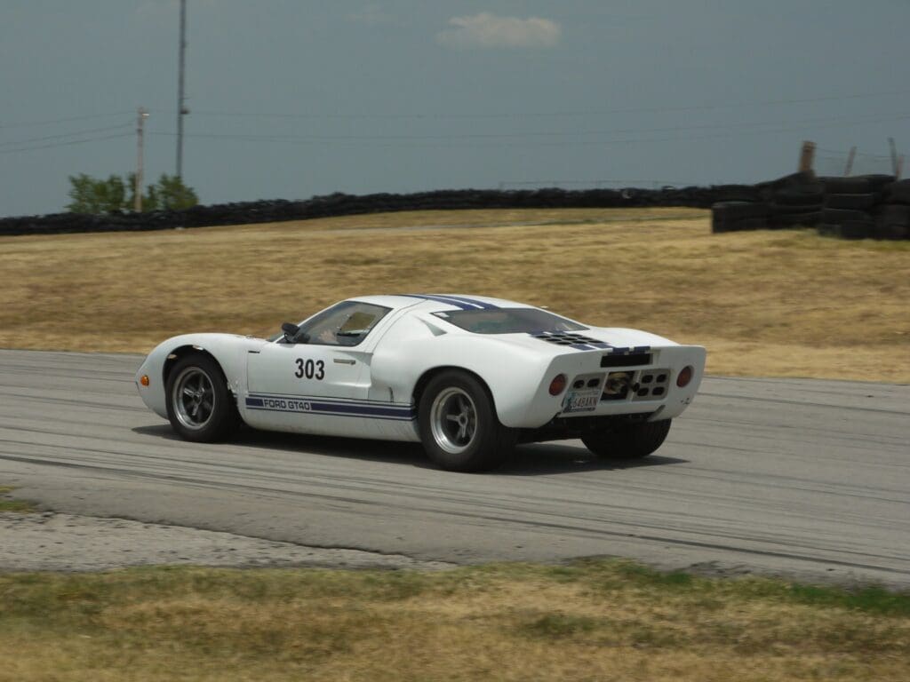 White vintage Shelby GT500 racing on a track.