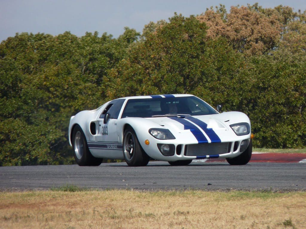 Classic white race car with blue stripes on a track.