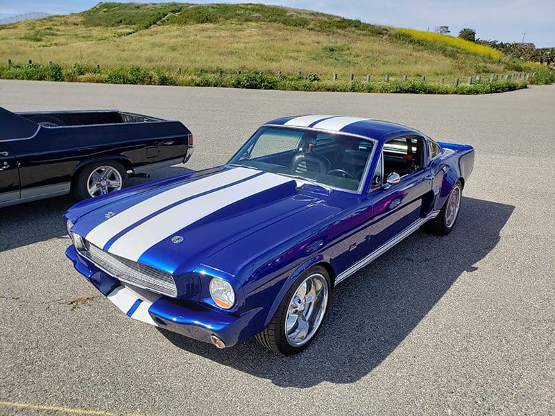 Classic blue and white Ford Mustang parked outdoors on a sunny day.