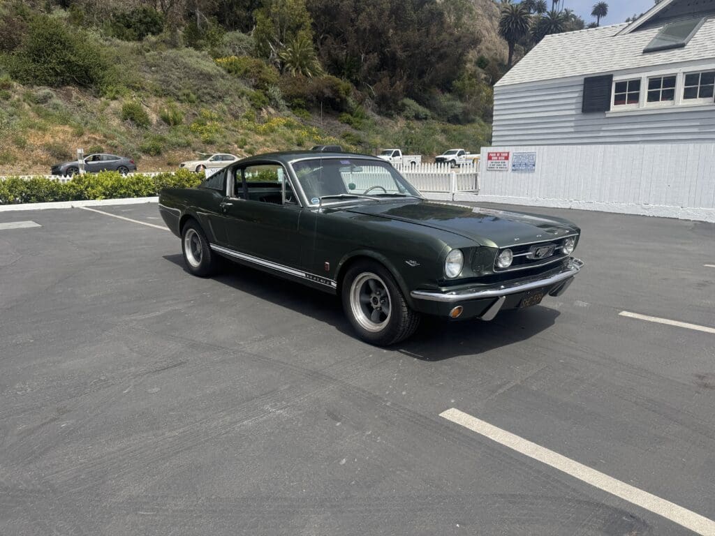 Classic dark green convertible Mustang parked outdoors on a sunny day.