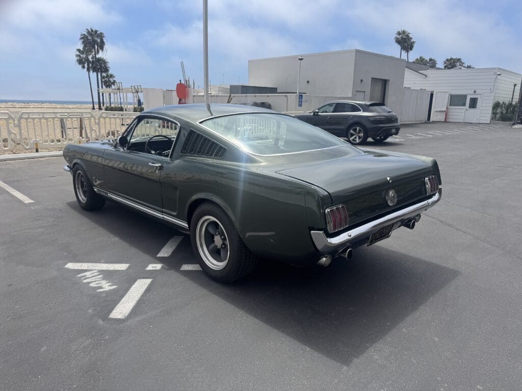 Classic dark green convertible Mustang parked outdoors on a sunny day.