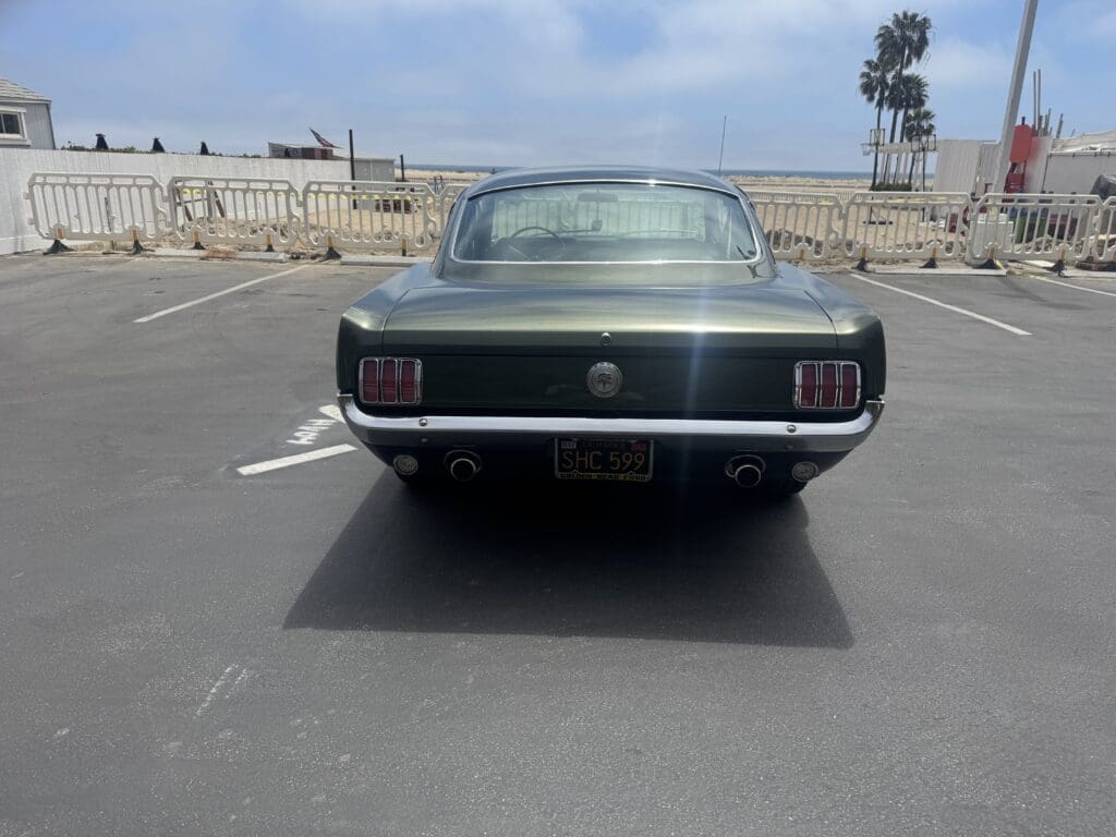 Rear view of a classic dark green Ford Mustang parked outdoors.
