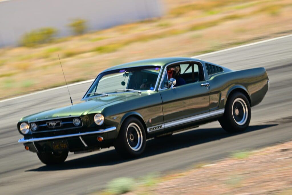 A sleek black vintage muscle car speeding on a race track.