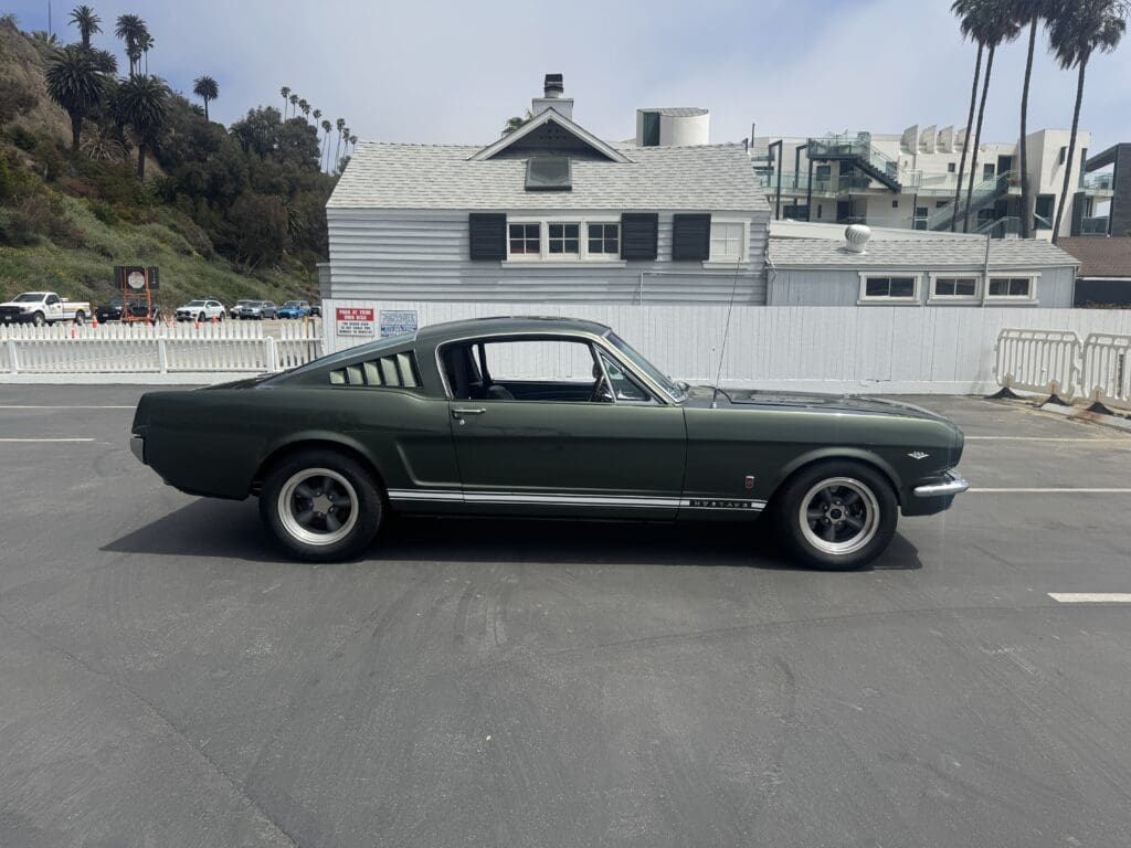 Classic dark green Ford Mustang parked outdoors on a paved surface.