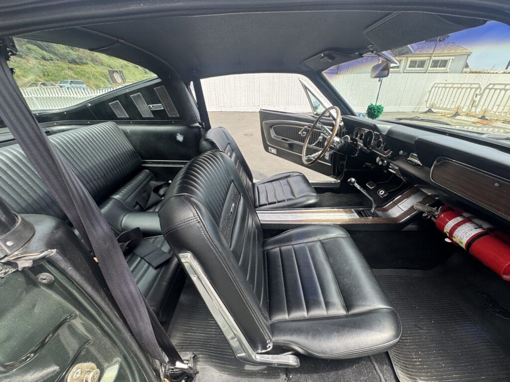 Interior view of a classic car with black leather seats and vintage dashboard.