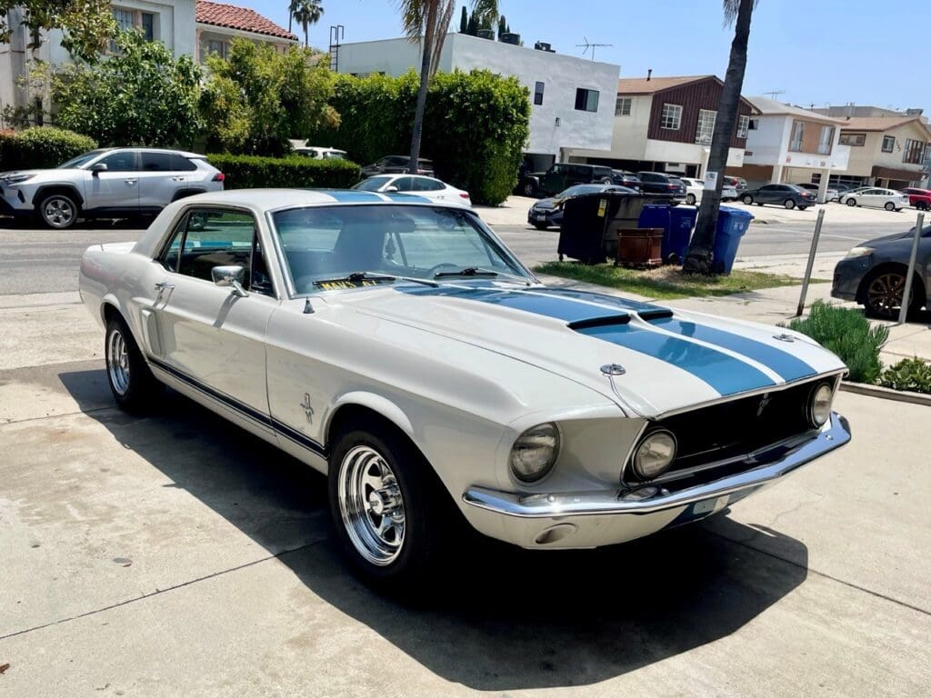 Classic white vintage Ford Mustang parked on a sunny street.