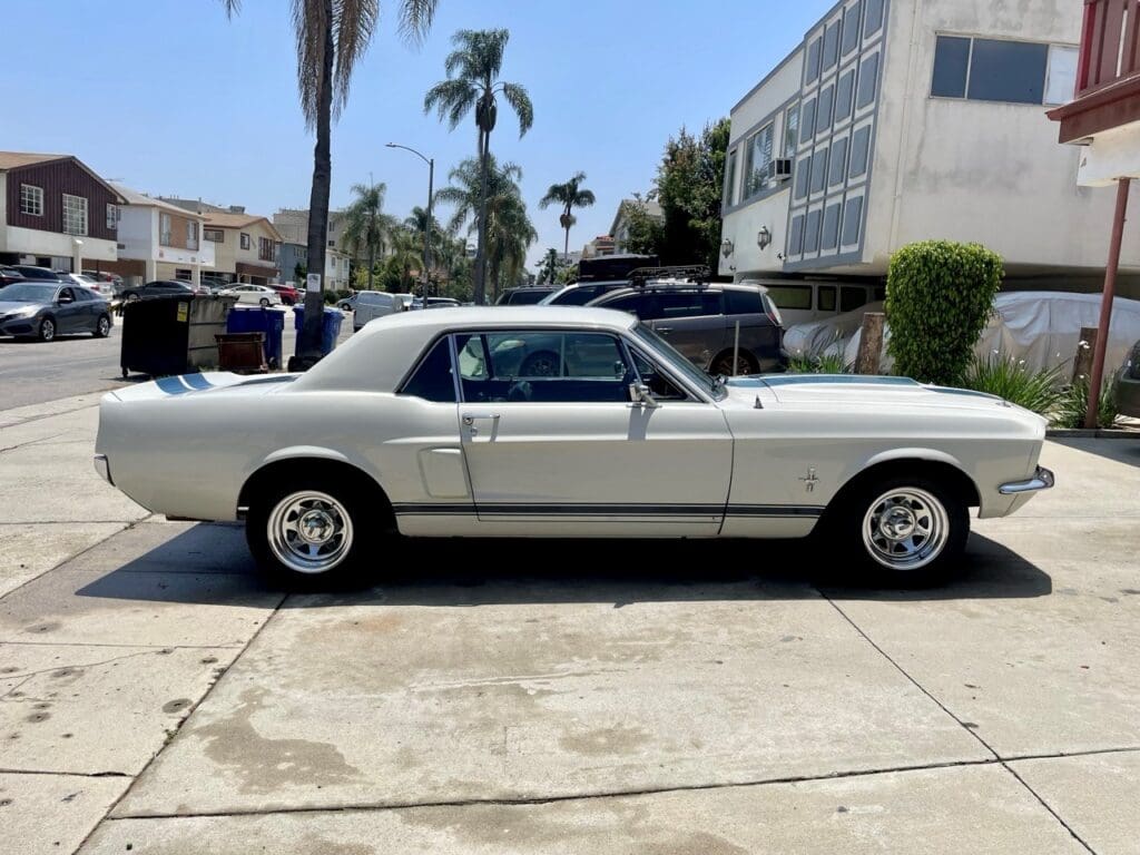 Classic white Ford Mustang parked outdoors on a sunny day.