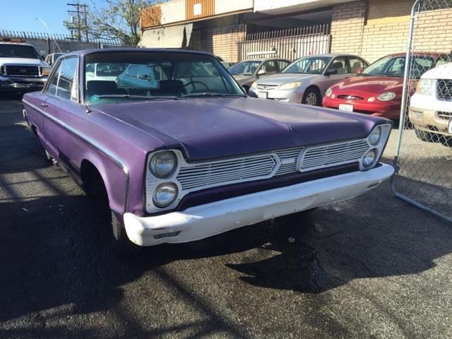 Classic purple vintage car parked outdoors on a sunny day.