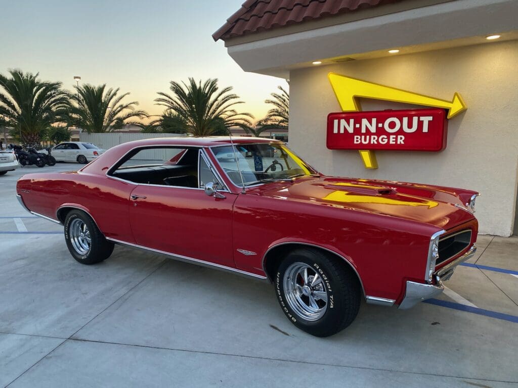 Classic red muscle car parked outside an In-N-Out Burger.