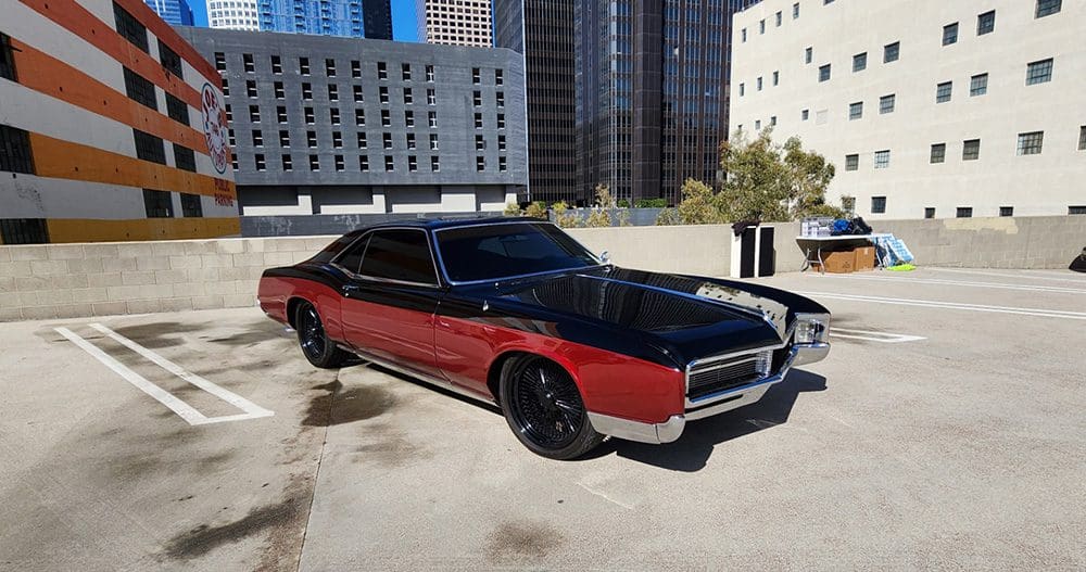 Classic red and black convertible car parked in an urban setting.