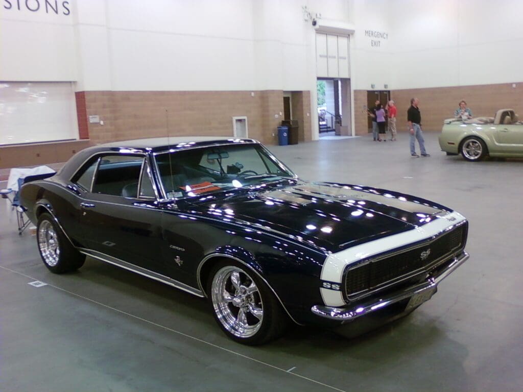 Classic black 1960s muscle car on display indoors.