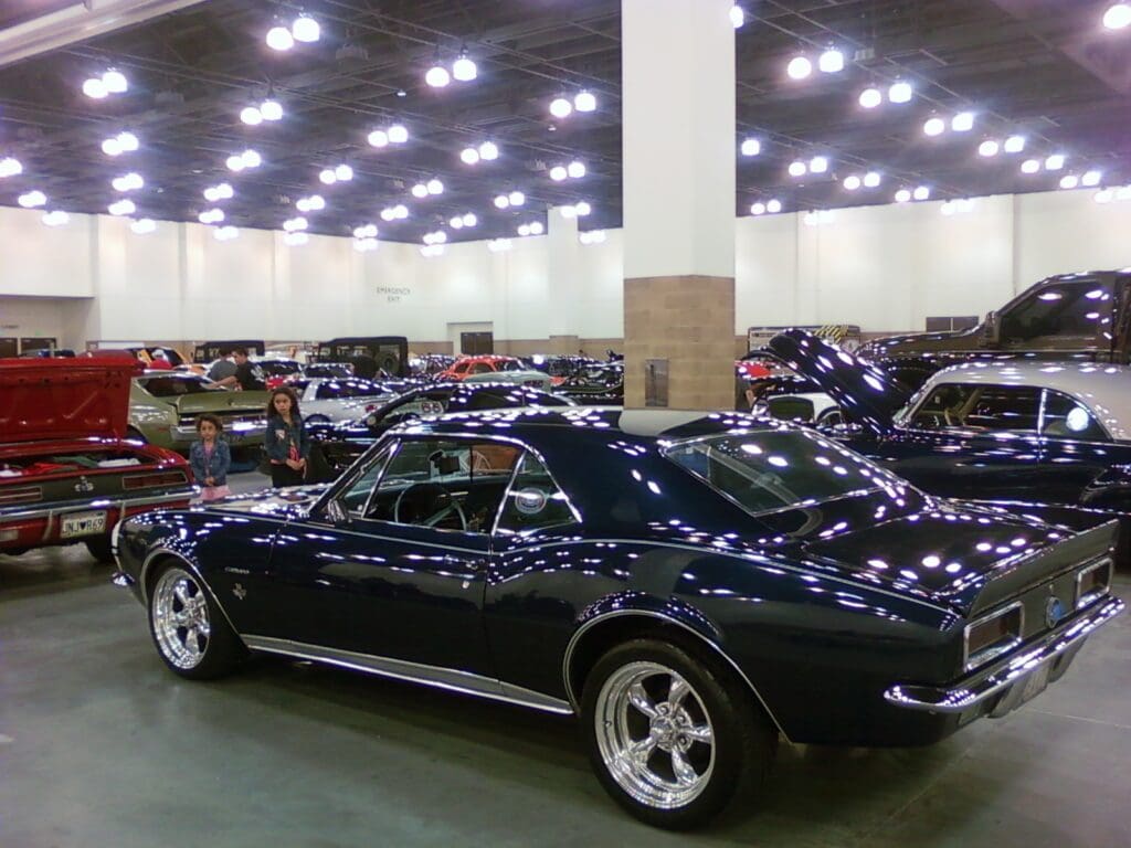 Classic black Corvette on display in a spacious indoor car show.