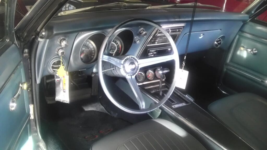 Classic car interior with vintage steering wheel and dashboard.