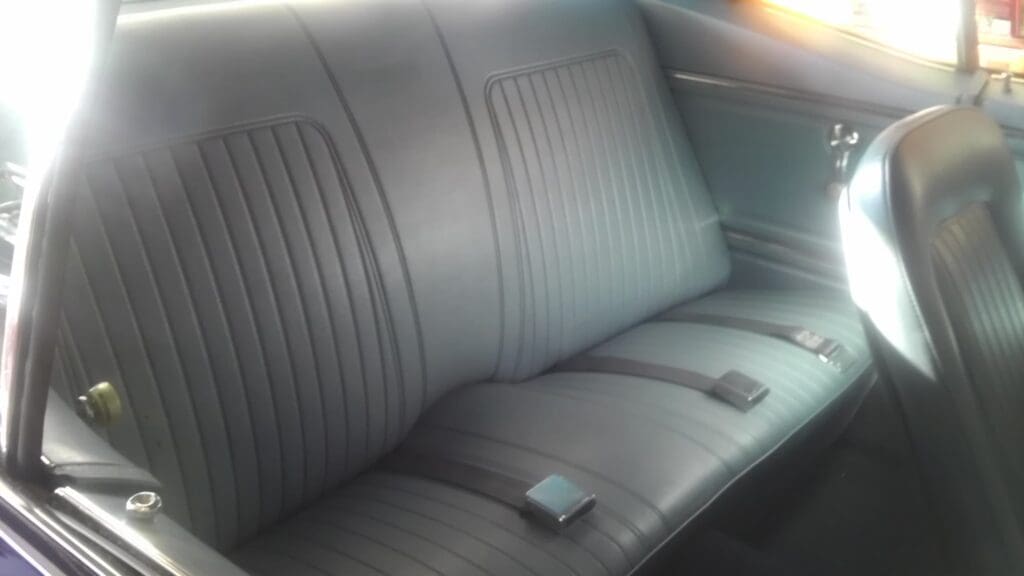 Gray leather car backseat with seat belts.