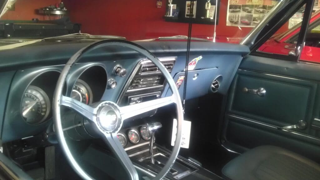 Classic car interior with vintage dashboard and steering wheel.