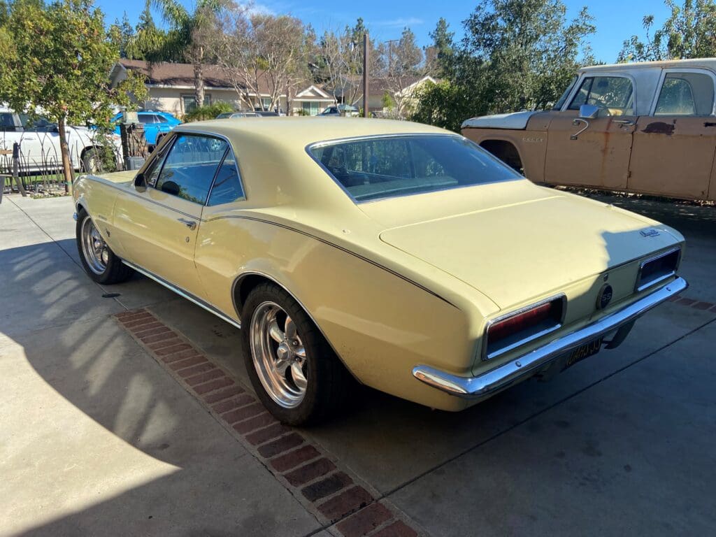 Classic yellow muscle car parked outdoors at a car show.