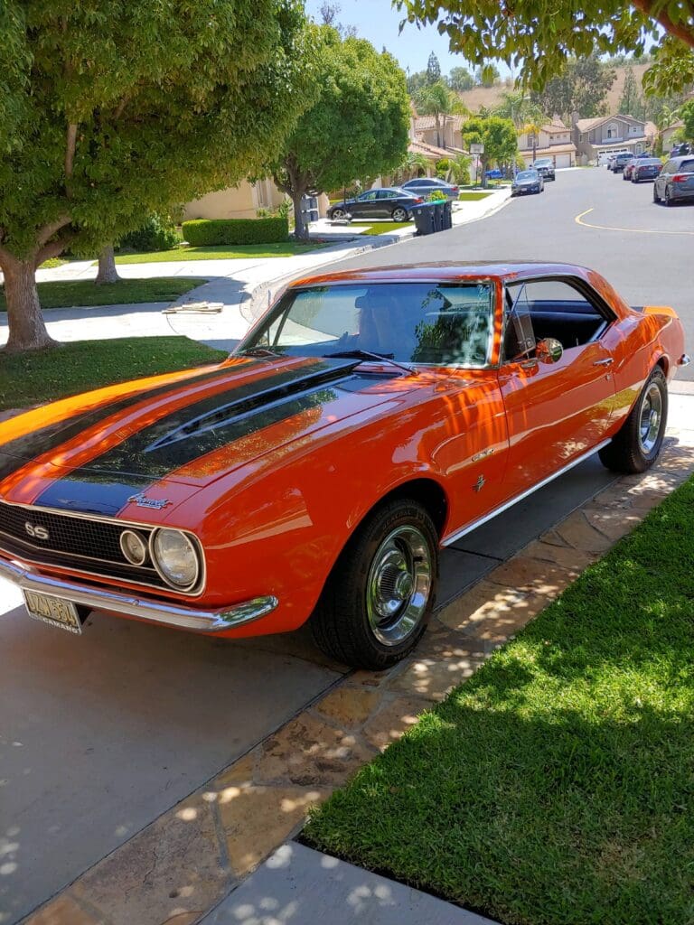 Classic orange muscle car parked on a sunny residential street.