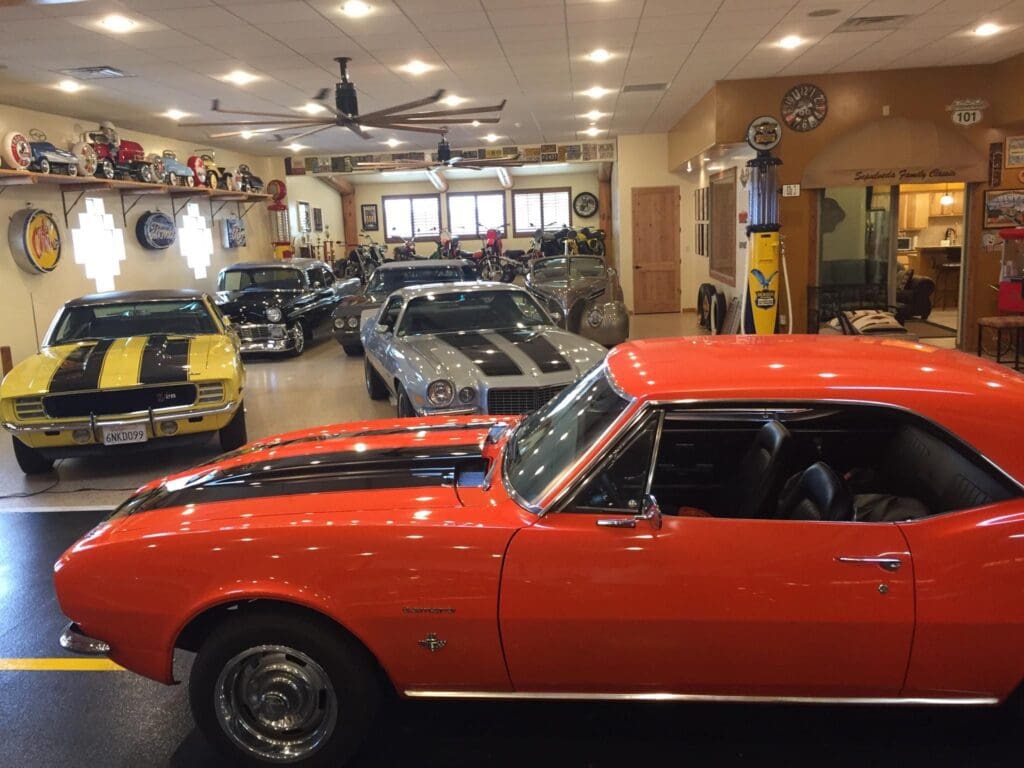 A vibrant orange classic car in a showroom filled with vintage vehicles.