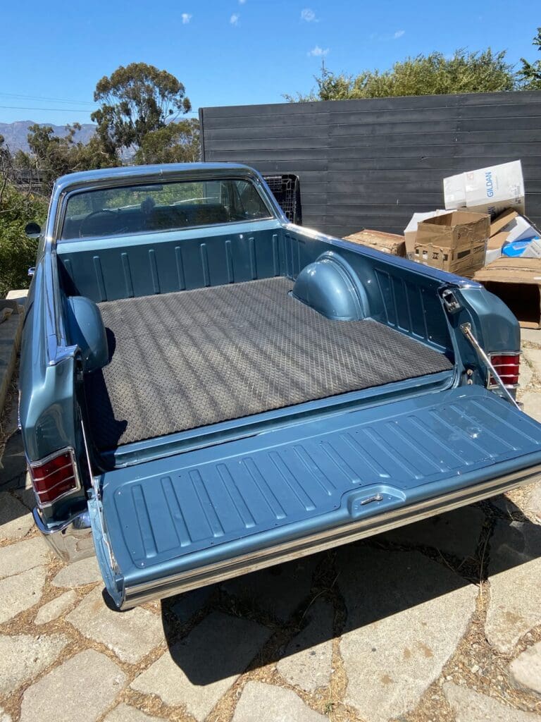Classic blue convertible car parked in a lot on a sunny day.