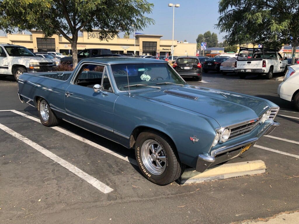Classic blue muscle car parked in a lot on a sunny day.