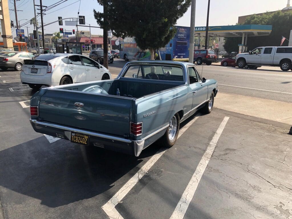 Classic blue muscle car parked in a lot on a sunny day.