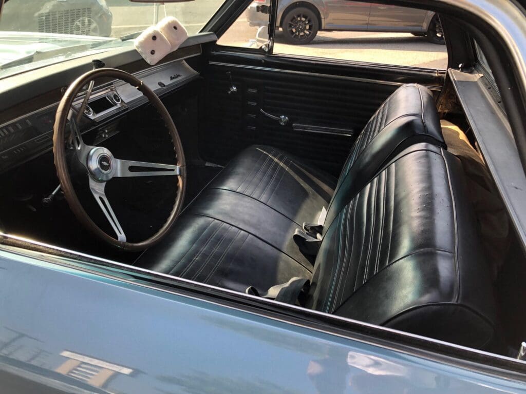 Interior of a vintage car with black leather seats and classic steering wheel.