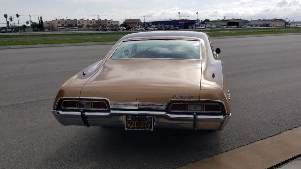 Classic beige vintage car parked outside a garage.