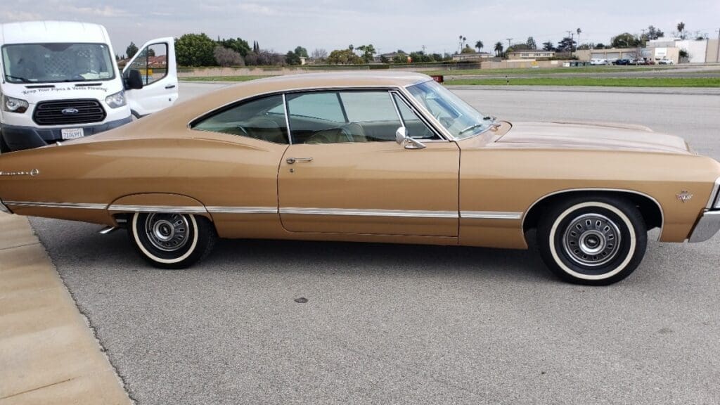 Classic beige vintage car parked on a road.