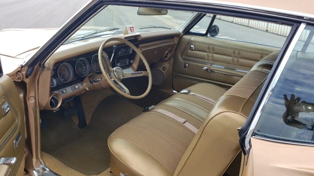 Classic car interior with tan seats and vintage dashboard.
