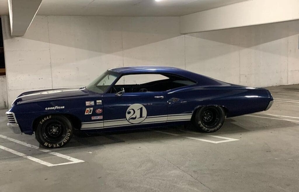 Classic blue race car with number 21 in a parking garage.