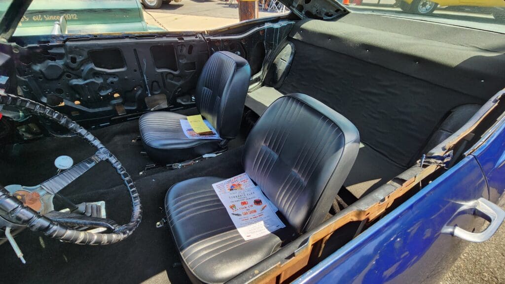 Interior of a vintage car showing two black seats and the dashboard.