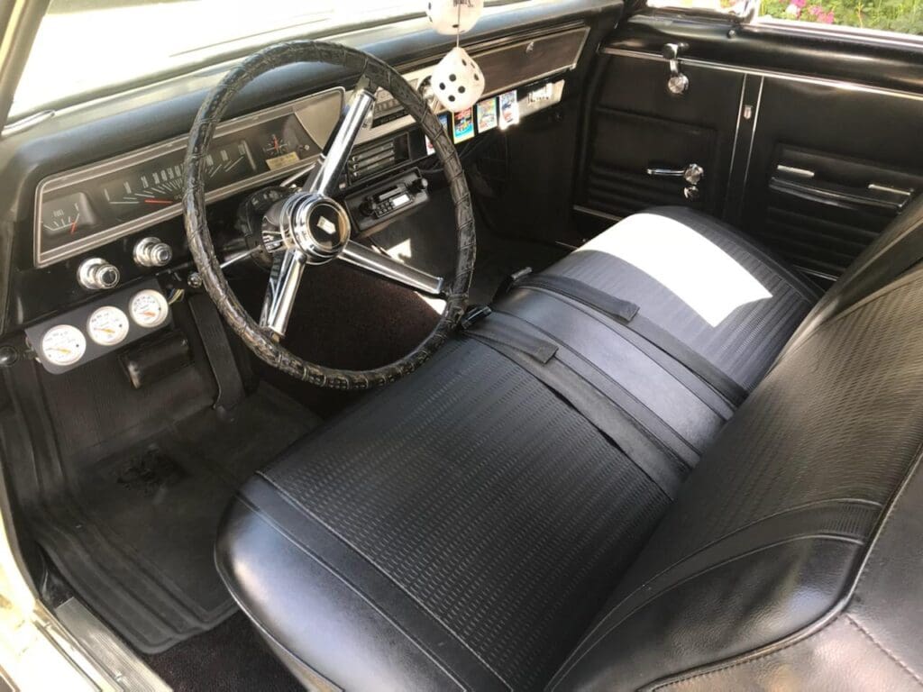 Vintage car interior with classic steering wheel and black bench seat.