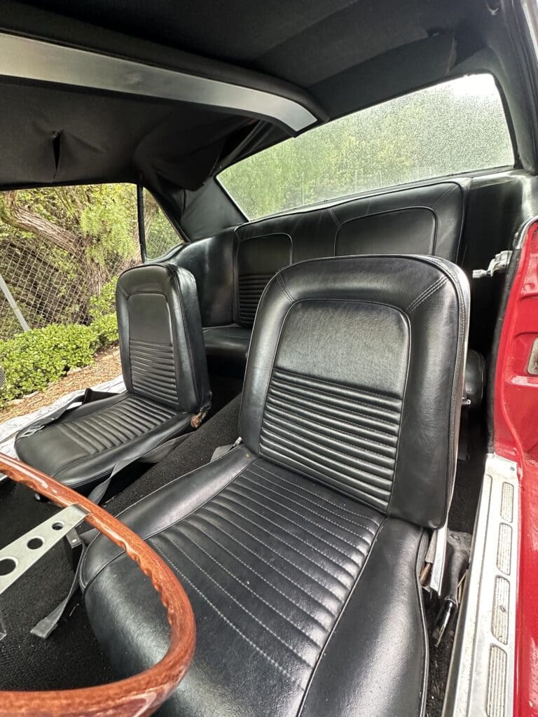 Black leather car seats inside a vintage vehicle.
