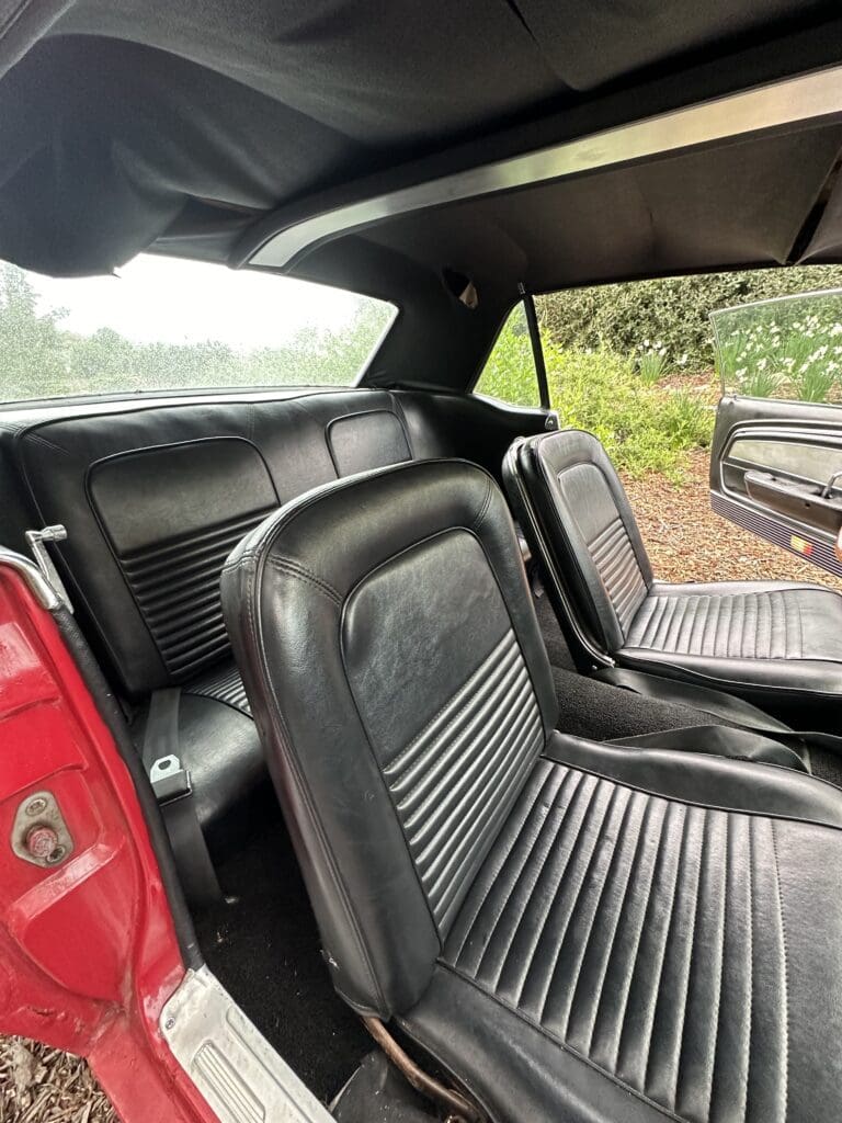 Interior view of a classic red car with black leather seats.