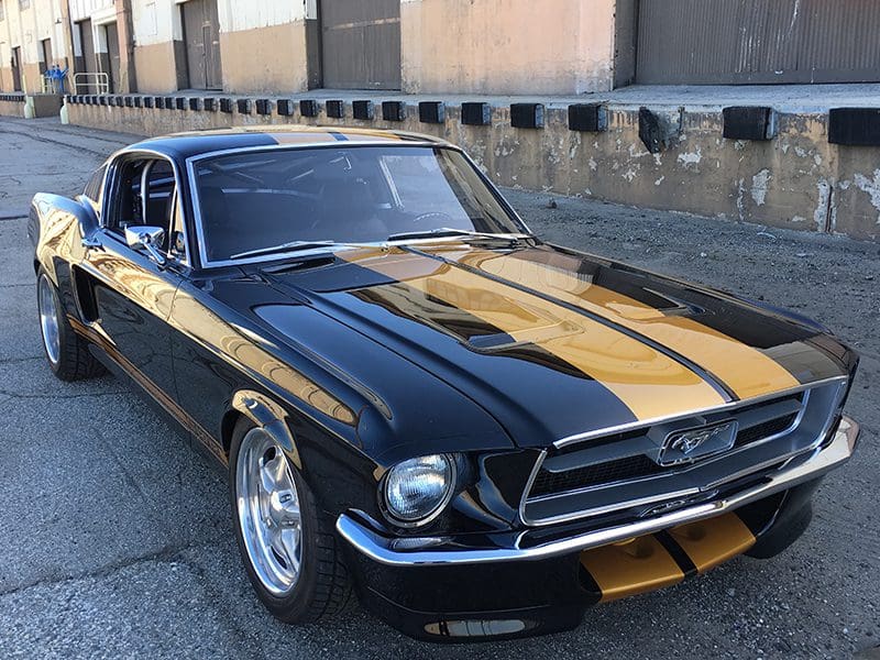 Classic black and gold Ford Mustang parked on a street.