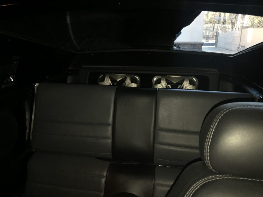 Interior of a car with black leather seats and a rear speaker system.