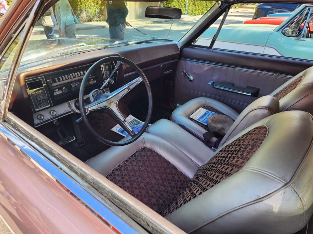 Interior view of a vintage car with classic steering wheel and patterned seats.