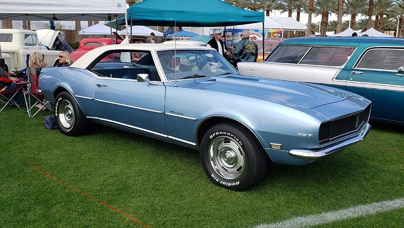 Classic light blue 1960s muscle car on display at an outdoor car show.