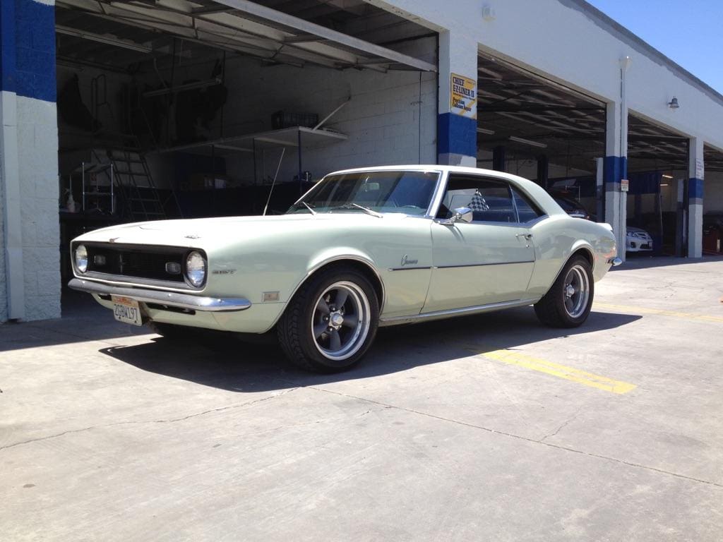 Classic light green 1967 Chevrolet Camaro parked outside a garage.