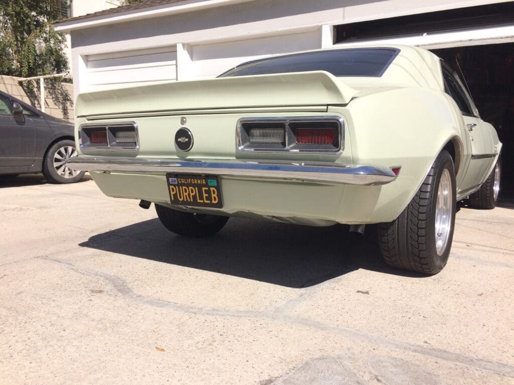 Classic light green 1967 Chevrolet Camaro parked outside a garage.
