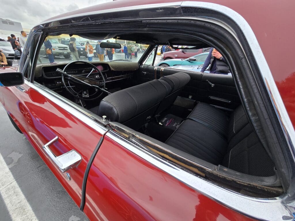 Classic red vintage car parked on a cloudy day.