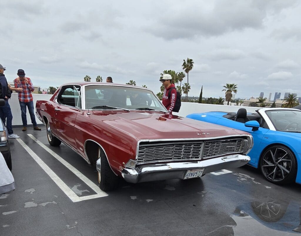 A classic red convertible car parked under a cloudy sky.
