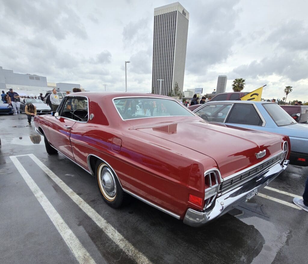 Classic red vintage car parked in a lot on a cloudy day.