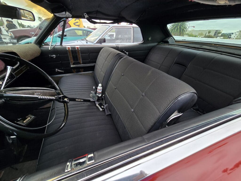 Interior of a vintage car showing front bench seat and steering wheel.