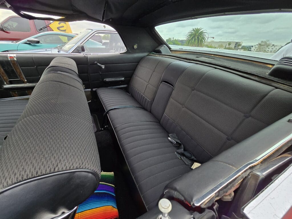Interior view of a classic car's rear seats and back window.