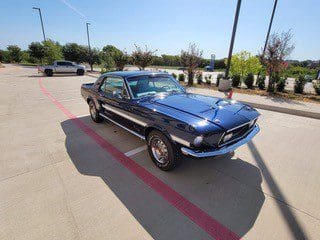 Classic blue Ford Mustang parked outdoors on a sunny day.