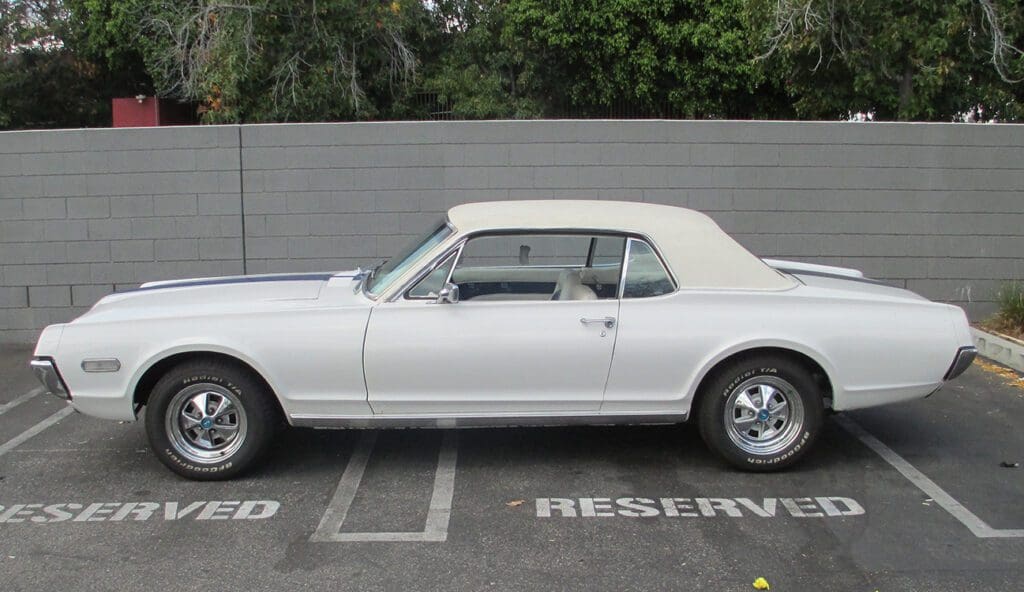 Classic white convertible car parked in a reserved spot.