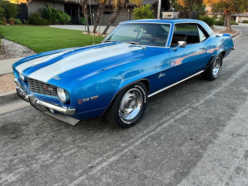 A classic blue 1969 Chevrolet Camaro parked on a driveway.
