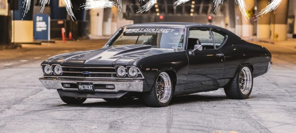 A sleek black classic muscle car parked indoors with polished wheels.