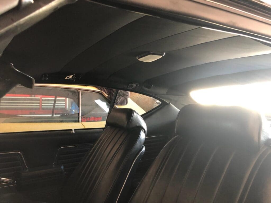 Interior view of a car showing front and back black leather seats.